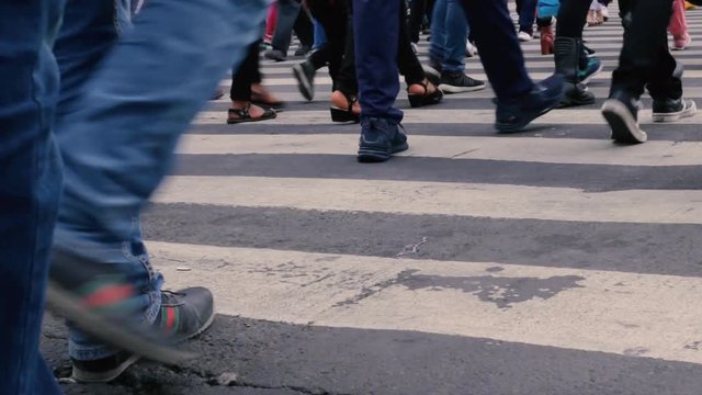 Pies y piernas de personas cruzando la calle