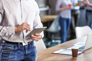 Young man with tablet computer during business meeting in office