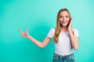 Fototapeta premium Portrait of cheerful lady showing promotion ads wearing denim jeans touch her cheeks with hands screaming isolated over teal turquoise background