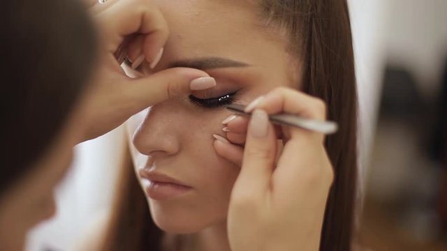 Model have a makeup by makeup artist in beauty salon. First person view. Redhead model with freckles. Close up of model's face with make up