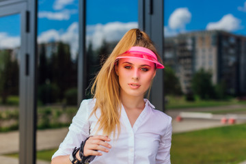 Portrait of an emotional girl in a pink cap visor and protective gloves for rollerblades and...