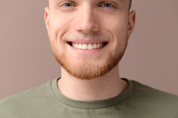 Young man with healthy teeth on color background