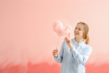 Beautiful woman with cotton candy on color background