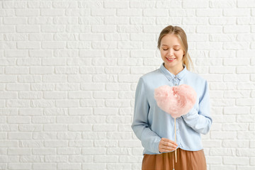 Beautiful woman with cotton candy on white brick background