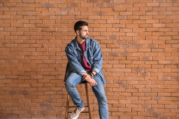 Fototapeta na wymiar Fashionable young man near brick wall