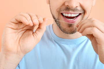 Man flossing teeth on color background, closeup