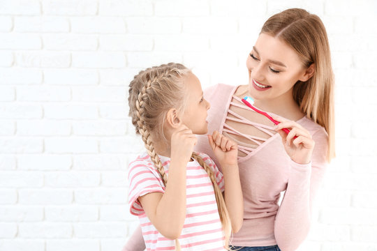 Woman and her little daughter cleaning teeth on white background - Powered by Adobe