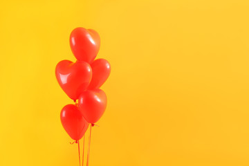 Heart-shaped air balloons on color background