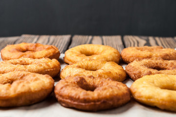 Lot of homemade baked donuts without cream lies on paper and old rustic wooden table