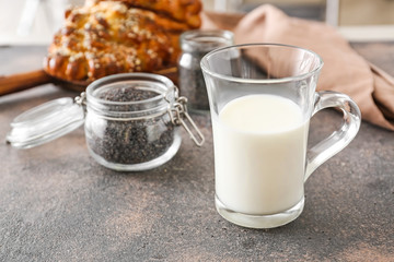 Jar with poppy seeds and glass of milk on table
