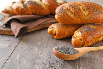Spoon with with poppy seeds and pastry on wooden table