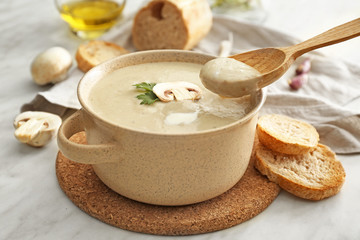 Pot of tasty mushroom cream soup on table