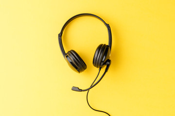 Call center concept with helpdesk headphones on yellow background with copyspace