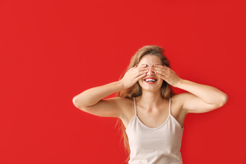 Young woman covering her eyes on color background