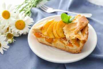 Plate with piece of tasty peach pie on table
