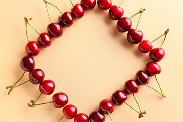 Frame made of sweet ripe cherry on color background