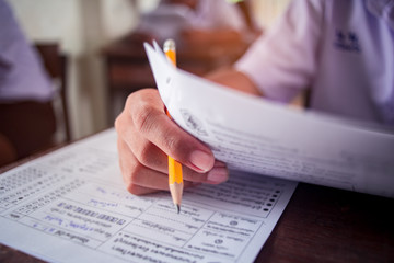 Exam with uniform school student doing educational test with stress in classroom