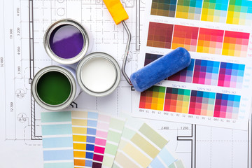 Cans of paint with roller, palette samples and house plan