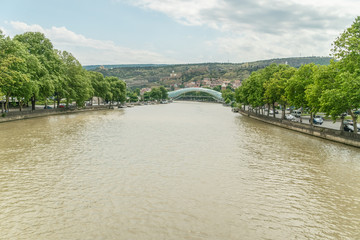 Fototapeta na wymiar Peace Bridge in Tbilisi. View of the futuristic bridge of glass and metal across the Kura River