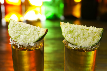 Shots of tasty tequila with lime and salt on table, closeup