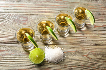 Shots of tasty tequila with lime and salt on wooden table
