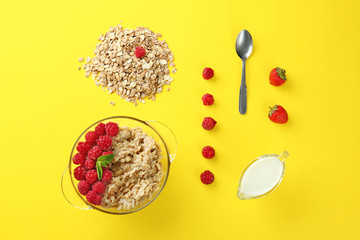 Bowl with tasty sweet oatmeal, milk and berries on color background