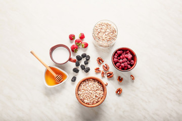 Oat flakes with milk, honey, nut and berries on light table