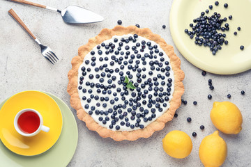 Composition with tasty bilberry pie on light background