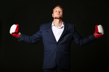 Businessman in boxing gloves against dark background