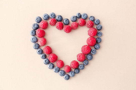 Heart made of ripe berries on light background