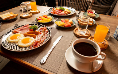 Breakfast on the table is bacon, fried egg, coffee, tea, bread.