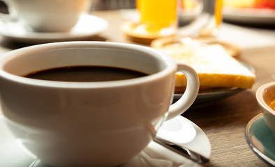 Breakfast on the table is bacon, fried egg, coffee, tea, bread.