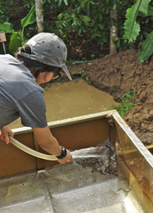 Female miner wearing grey cap and shirt washing gemstone rocks in stainless steel tray to screening and selecting best quality gems