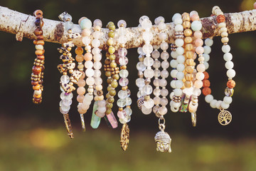 Collection of mineral stone beaded bracelets on natural outdoor background - obrazy, fototapety, plakaty