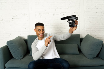 Young happy blogger recording video on camera for internet blog