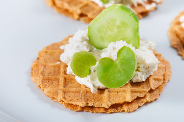 Salty waffles with cheese, herbs, cucumber on a light background.