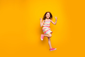 Fototapeta na wymiar Full size photo of cheerful kid jumping making v-signs isolated over yellow background
