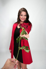 Fototapeta na wymiar Jolie jeune femme habillée en rouge avec un rose pour la Saint Valentin