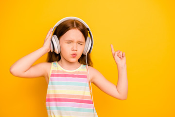 Obraz na płótnie Canvas Portrait of charming kid wearing tank-top singlet with closed eyes listening music isolated over yellow background