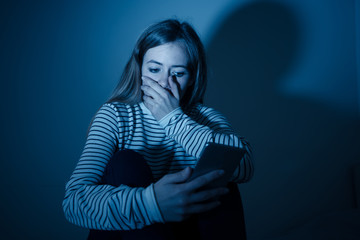 Depressed teenager girl on mobile phone victim of cyberbullying feeling sad, unhappy and lonely