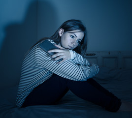 Depressed teenager girl on mobile phone victim of cyberbullying feeling sad, unhappy and lonely