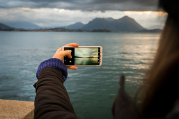 woman with phone taking a picture in a lake 