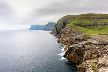 Bosdalafossur waterfall panorama with cliff rocks and rain cloud on horizon. Vagar,  Faroe Islands.