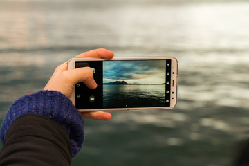 woman with phone taking a picture in a lake 