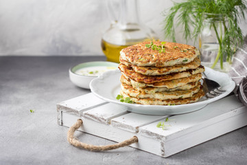 Chicken pancakes with zucchini and herbs, stack of cutlets on plate. Delicious summer food, healthy lunch with meat, vegetables, yogurt sauce