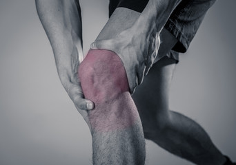 Sport man injured when exercising or running holding his knee in pain