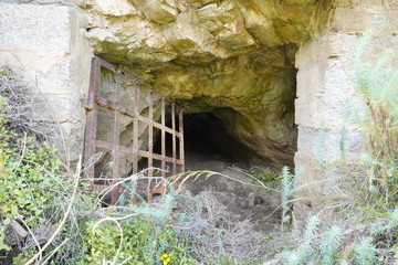 Lost places, Rusty grid barrier in front of a cave in Argientiera