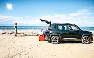 Fototapeta na wymiar A woman in a black car on a sandy beach and blue ocean view.