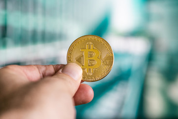 Male hand hold a bitcoin, modern office buildings in the background, bitcoin concept, business...