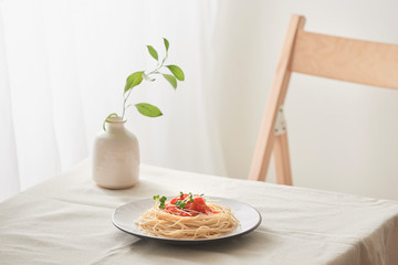 handmade pasta with ragout sauce on plate on vintage white table with colander and flowers